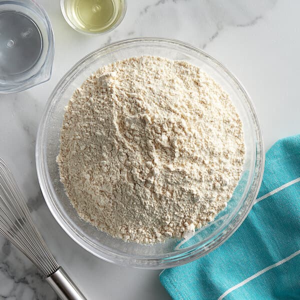 A bowl of Carnival King Belgian waffle mix with a whisk on a table.