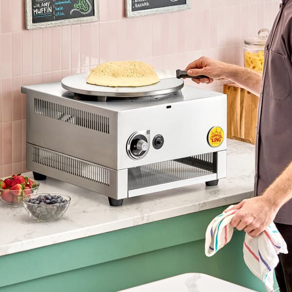 A stainless steel 16-inch liquid propane crepe maker with a crepe being cooked on its round griddle surface.