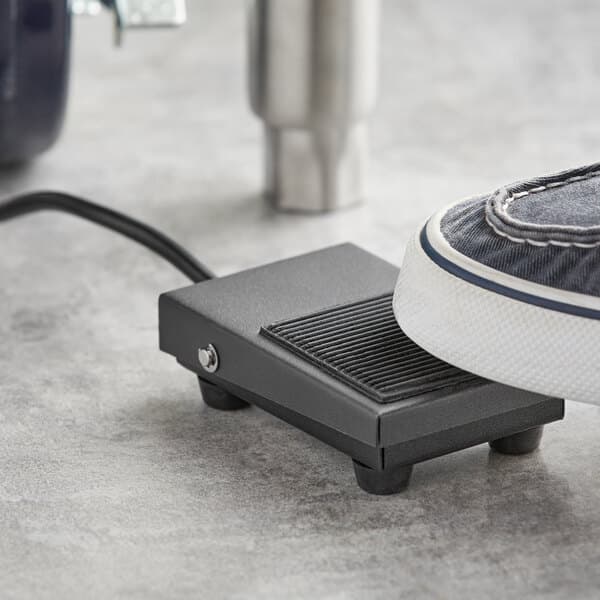 A foot on a foot pedal with a shoe on it.