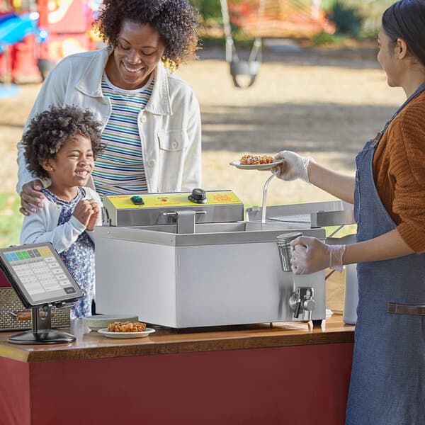 A woman and child at a Carnival King Funnel Cake stand.