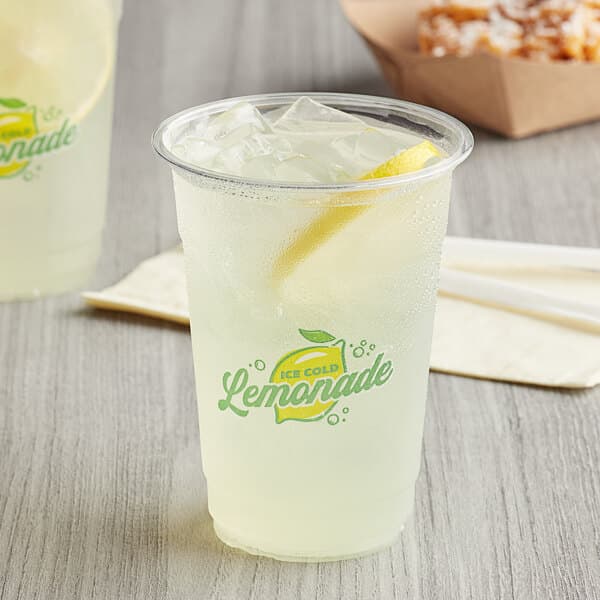 A clear plastic cup filled with ice-cold lemonade and a lemon slice, featuring a printed 'Lemonade' logo on the front.