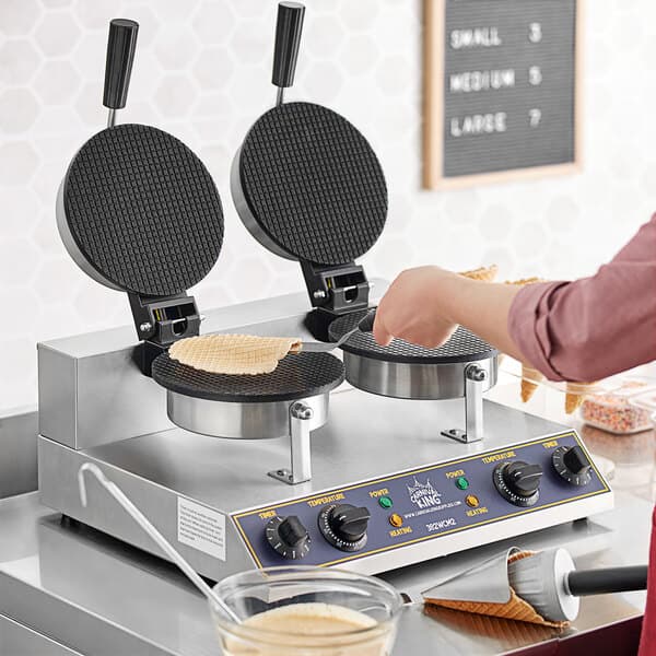 A woman making waffle cones on a Carnival King double waffle cone maker.