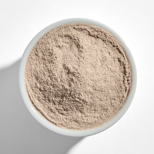 A white bowl filled with light brown cinnamon sugar popcorn seasoning powder.