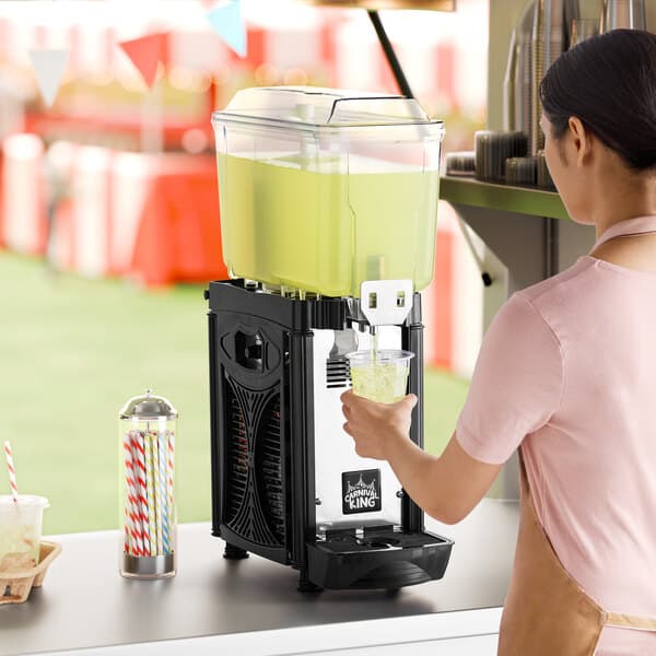 A single 3-gallon bowl refrigerated beverage dispenser filled with a yellow-green drink, being used by a person.
