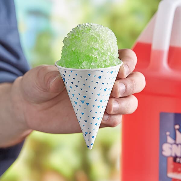 A person holding a Carnival King paper cone filled with green snow cone.