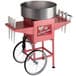 A pink Carnival King cotton candy machine with a silver bowl on a red cart.