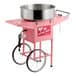 A pink cotton candy machine with a large stainless steel bowl and a wheeled cart.