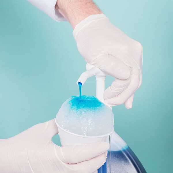 A person in white gloves pouring blue Carnival King Bubble Gum syrup over ice in a cup.