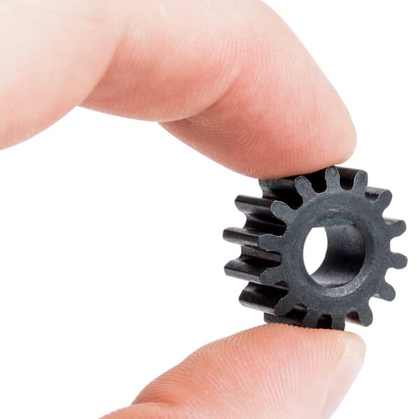 A finger holding a small black gear.