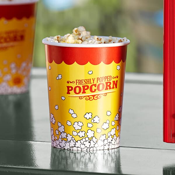 A yellow Carnival King popcorn cup filled with popcorn on a table.