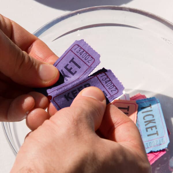 A pair of hands holding Carnival King purple raffle tickets.