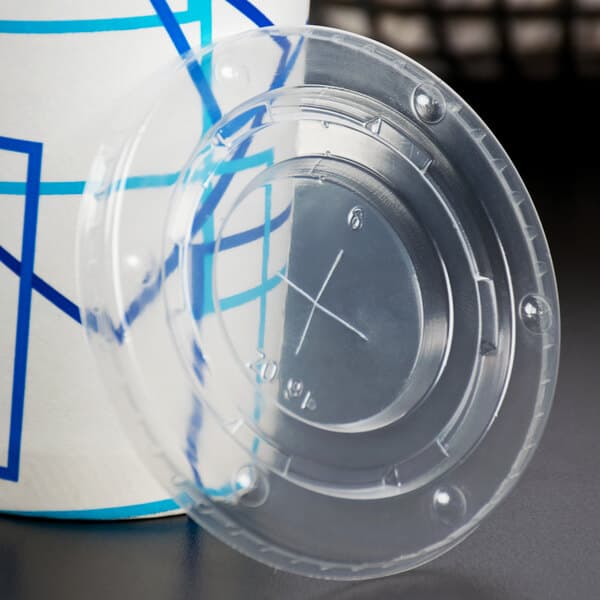 A Carnival King clear plastic lid with a straw slot on a clear lemonade cup.