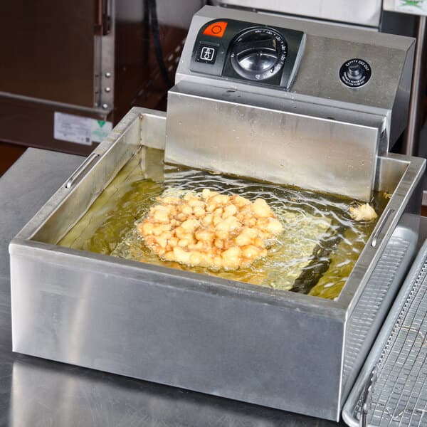A deep fryer with a Carnival King stainless steel funnel cake mold ring in it.
