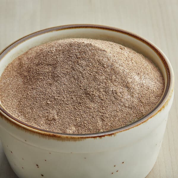 A bowl of Carnival King Salt and Pepper popcorn seasoning on a wooden table.