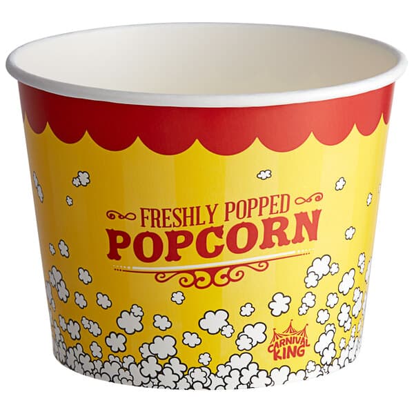 A yellow and red Carnival King popcorn bucket with white and red text full of popcorn.