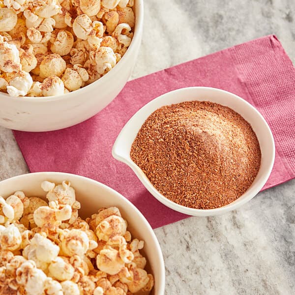 A bowl of Carnival King Kickin' Cajun popcorn and a bowl of brown powder.