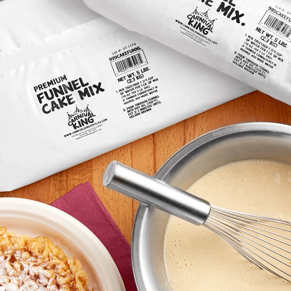 A bowl of Carnival King Funnel Cake Mix with a whisk in it.